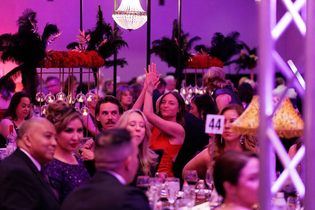 Woman clapping her hands above her head in a crowded room.